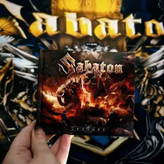 Ręka trzyma płytę "Legends" zespołu Sabaton. Tło zdobią grafiki z innych sabaton albumów.