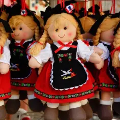 Uśmiechnięte lalki Zuzia w tradycyjnych strojach alzackich, z warkoczami i czarnymi fartuszkami. Nieduża zabawka, idealna do śpiewanki.