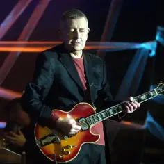 Artysta gra na gitarze, a na ekranie widać napis "vox szcześliwej drogi juz czas".