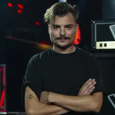 Wiktor Dyduła, z charakterystycznym wąsem i tatuażem węża, prezentuje swoje utwory na scenie Voice of Poland.