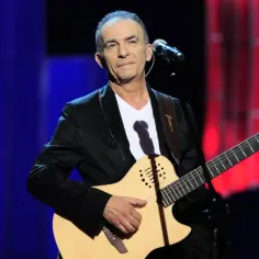 Seweryn Krajewski gra na gitarze, wykonując swoje piosenki na scenie.