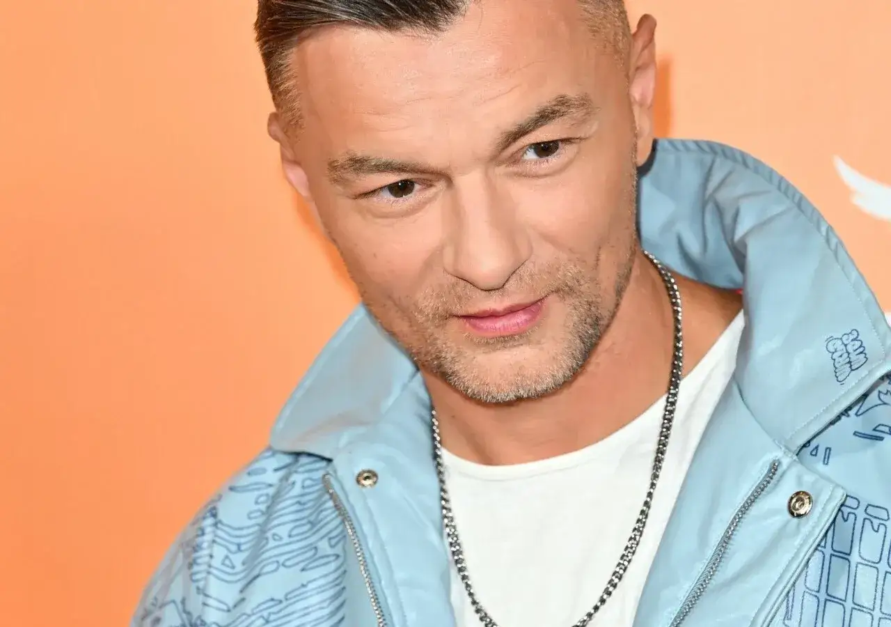 Liber w błękitnej kurtce, z łańcuchem na szyi, prezentuje swoje najnowsze liber utwory.